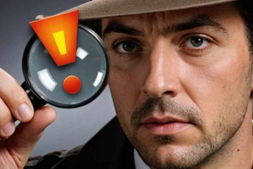 This image shows a close-up of a man with dark hair and slight beard, wearing a light brown fedora hat. He is holding a magnifying glass close to the camera, through which an exclamation mark symbol in bright orange with a yellow center is prominently displayed against a grey background. The man's facial expression is serious and focused, directing attention toward the symbol in the magnifying glass, suggesting importance or urgency. His gaze and the position of the magnifying glass suggest a moment of discovery or emphasis.